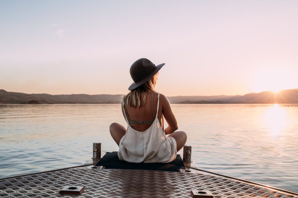 woman in hat enjoying sunset on pier